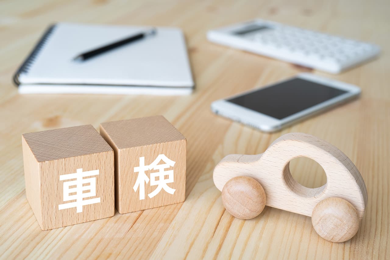 車検とかかれた木の置物と木のミニカーと筆記用具